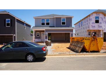 New two-story home with gray siding, visible construction materials, and an unfinished yard at 809 Ottawa Dr, Garner, NC 27529
