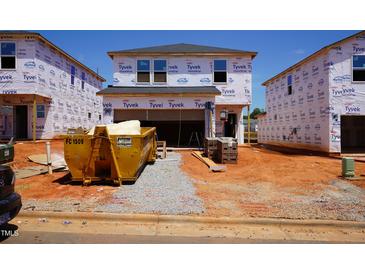 New home construction site featuring house with Tyvek wrap, yellow dumpster, and materials at 829 Ottawa Dr, Garner, NC 27529