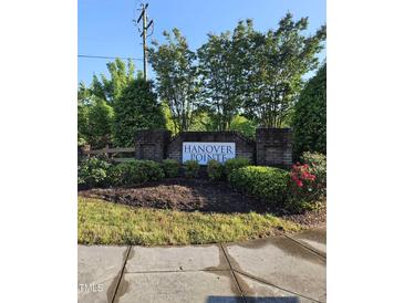 Entrance to Hanover Pointe featuring a brick sign surrounded by manicured landscaping and lush greenery at 1030 Thoughtful Spot Ln, Durham, NC 27703