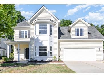 Inviting two-story home with a two-car garage, bay window and manicured lawn and yellow siding at 1148 Dexter Ridge Dr, Holly Springs, NC 27540
