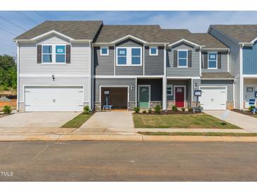 New construction townhomes with single car garages and colorful front doors on a sunny day at 1167 Abbott St, Mebane, NC 27302