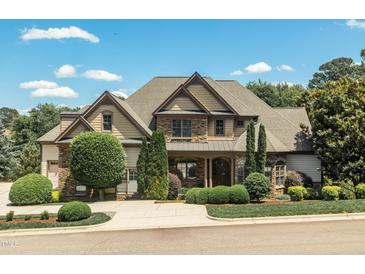 Two-story home featuring stone and siding with a well-manicured lawn and mature landscaping at 12317 Richmond Run Dr, Raleigh, NC 27614