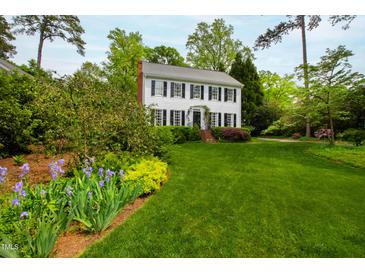 Charming two-story home with black shutters and a lush green lawn and well-manicured landscaping at 1904 Victoria Rd, Raleigh, NC 27608