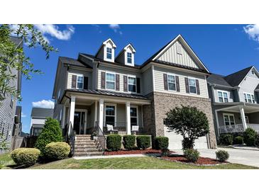 Charming two-story home with a brick-accented facade, covered front porch, and beautifully landscaped yard at 232 Hensley Hill Pl, Holly Springs, NC 27540