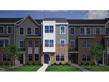 Charming townhome with a modern brick and siding exterior, complemented by green grass and landscaping at 364 Chesapeak Commons St # 133, Garner, NC 27529
