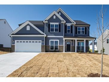 Two-story home featuring gray siding, a white garage door and black shutters under a clear blue sky at 50 Rosewood Ln, Youngsville, NC 27596