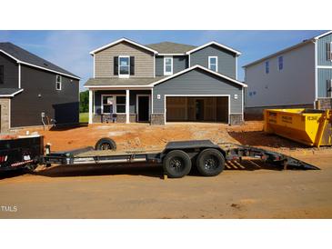 New two-story home featuring gray siding, an open garage, a front porch with space for seating, and unfinished landscaping at 712 Deschutes Dr, Garner, NC 27529