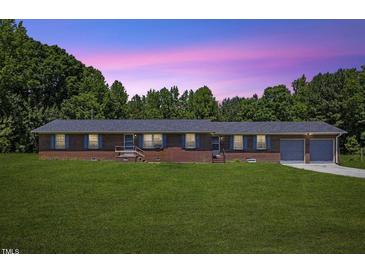 Charming single-story brick home with an attached two-car garage and well-manicured front lawn at 137 Vaiden Rd, Louisburg, NC 27549