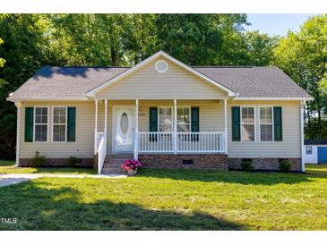 Charming home features a quaint front porch, green shutters, a well-manicured lawn, and an inviting entryway at 1443 Smokey Mountain Dr, Zebulon, NC 27597