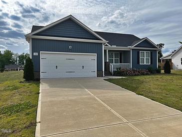 Inviting home with a two-car garage, manicured lawn, and charming front porch at 152 Springtooth Dr, Zebulon, NC 27597