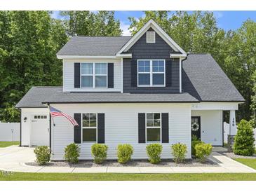Charming two-story home featuring a white facade, black shutters, and a well-manicured lawn with an American flag at 159 Mitchell Manor Dr, Angier, NC 27501