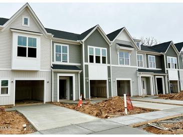 New construction townhomes show attached garages and concrete driveways on an overcast day at 166 Ripple Way # 323, Clayton, NC 27520