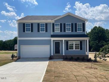Two-story home featuring a two-car garage, a black front door, and double-hung windows under a blue sky at 24 Grove Township Way, Angier, NC 27501