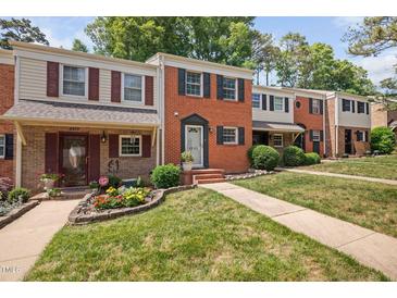 Traditional brick townhomes showcasing well-manicured lawns and charming curb appeal with colorful flowerbeds at 6565 New Market Way, Raleigh, NC 27615