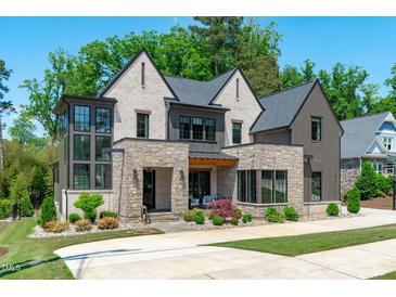 Handsome two-story home featuring brick, stone, and wood accents on a manicured lawn at 702 Wimbleton Dr, Raleigh, NC 27609
