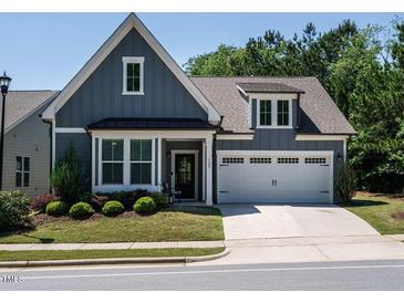 Charming home with blue siding, a two-car garage, manicured lawn, and a welcoming front porch at 725 Banningford Rd, Cary, NC 27518