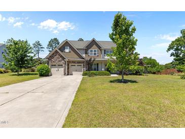 Charming two-story home featuring a stone facade, multi-car garage and a well-manicured lawn at 870 Kentucky Derby Ln, Lillington, NC 27546