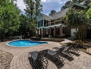 Beautiful backyard pool area with a fountain, lounge chairs, and mature landscaping creating a private oasis at 91 E Walker Woods Ln, Clayton, NC 27527