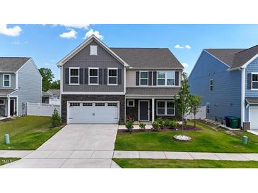 Charming two-story home featuring stone accents, a two-car garage, and professionally landscaped front yard at 1305 Addison Lake St, Fuquay Varina, NC 27526