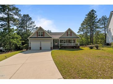 Charming home featuring a two-car garage, inviting front porch, and well-manicured lawn at 15 Clearwater Harbour Hbr, Sanford, NC 27332