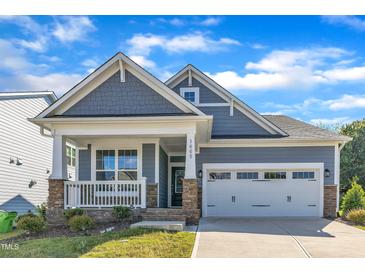 Charming home featuring a two-car garage, covered porch with stone accents and beautifully maintained lawn at 1665 Wilde Bnd, Apex, NC 27523