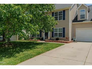Charming two-story home featuring a well-manicured lawn, blue shutters, and an attached two car garage at 2412 Chartwell Ln, Graham, NC 27253