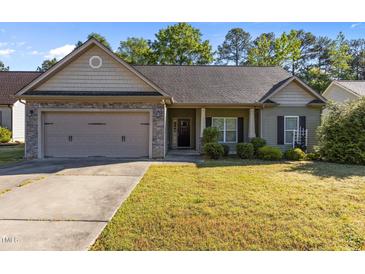 Charming single-story home with a two-car garage, stone accents, and well-maintained landscaping at 309 Coachman'S Trl, Stem, NC 27581