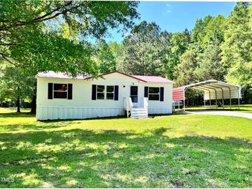 Charming single-story home with a metal carport, lush green lawn, and mature trees at 6579 Sidney Cottrell Rd, Oxford, NC 27565