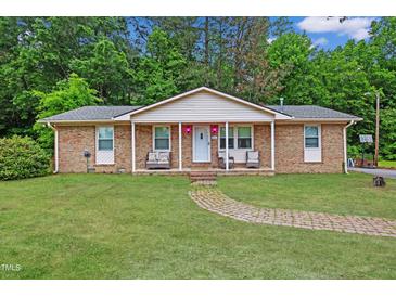 Charming brick home with a well-maintained front yard and inviting entrance with rocking chairs on the porch at 901 Currin Perry Rd, Zebulon, NC 27597