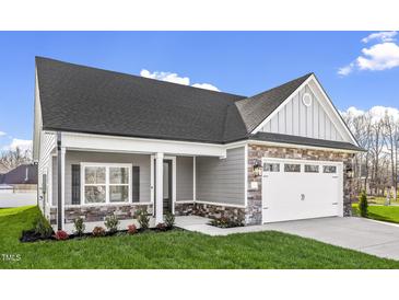 Charming home with stone accents, gray siding, manicured lawn, and a convenient attached two-car garage at 1009 Rhino Bnd, Oxford, NC 27565