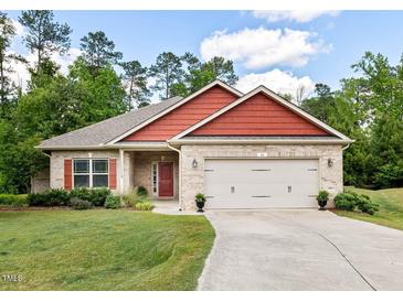 Charming brick home with red accents, manicured lawn and a two-car garage at 11 Woodwater Cir, Lillington, NC 27546