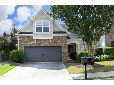 Charming home showcasing a stone facade, gray garage door, and manicured landscaping in a serene setting at 12306 Mossgreen St, Raleigh, NC 27614
