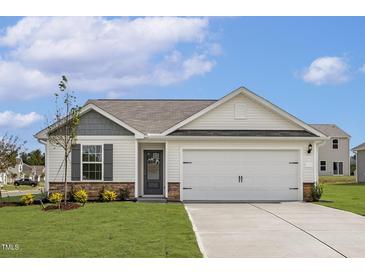 Charming single-story home featuring a well-maintained lawn, two car garage, and welcoming front entrance at 203 Benton Dr, Oxford, NC 27565