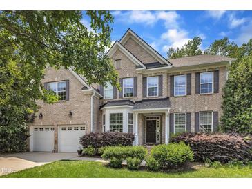 Charming two-story brick home featuring a well-manicured lawn, attached two-car garage, and beautifully landscaped front yard at 205 Forbes Rd, Wake Forest, NC 27587