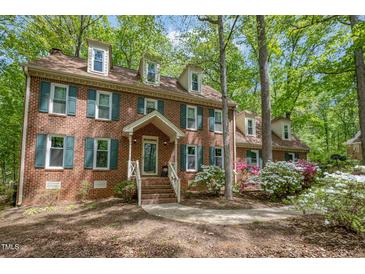 Charming brick home featuring dormer windows, green shutters, and a well-maintained front yard with mature trees at 309 Appaloosa Trl, Bahama, NC 27503