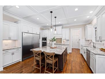 Bright, open kitchen featuring a large island, stainless steel appliances, and white cabinetry and hardwood floors at 3209 Bryant Falls Ct, Raleigh, NC 27613