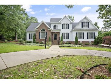 Beautiful two-story home with a manicured lawn, brick and siding accents, and a circular driveway at 4812 Cornoustie Ct, Holly Springs, NC 27540