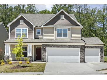 Charming two-story home with a three-car garage and stone accents, complemented by a well-maintained lawn at 605 Hampton Crest Ct, Fuquay Varina, NC 27526