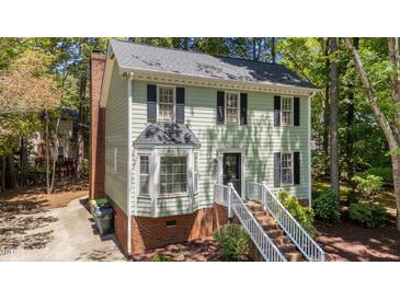 Charming two-story home with light green siding, black shutters, and landscaped front yard, creating great curb appeal at 6904 Sandringham Dr, Raleigh, NC 27613