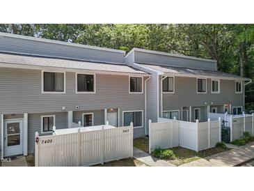 View of the townhouse featuring gray siding and a white picket fence in front of the property at 7407 Sandy Creek Dr, Raleigh, NC 27615