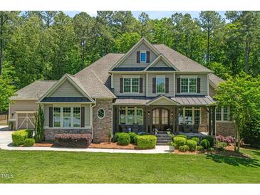 Charming two-story home with a manicured lawn, stone accents, and a welcoming front porch at 7544 Hasentree Club Dr, Wake Forest, NC 27587