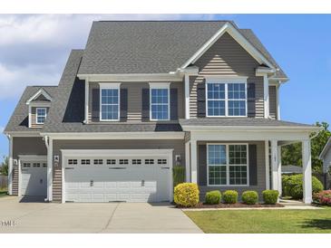 Charming two-story home featuring a two-car garage, gray siding, and a well-manicured lawn with fresh landscaping at 107 Southern Acres Dr, Fuquay Varina, NC 27526