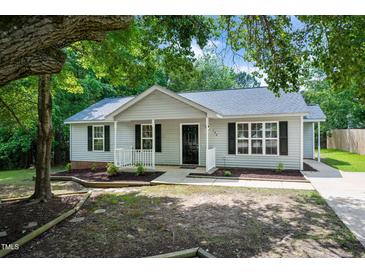 Charming single-story home featuring a covered front porch, manicured landscaping, and black window shutters at 144 Holly Mountain Rd, Holly Springs, NC 27540