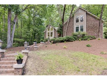 Charming brick and siding home with mature trees and brick stairs leading to the front door at 201 Red Bud Ln, Chapel Hill, NC 27514