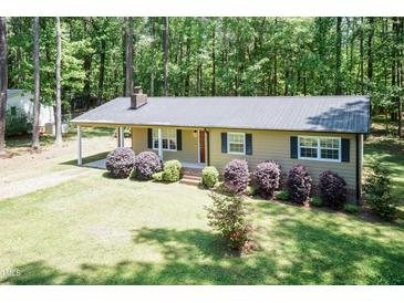 Charming single story home featuring a metal roof, well-maintained lawn, and mature trees in a quiet, wooded setting at 4221 River Run Dr, Sanford, NC 27332