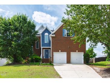 Inviting two-story brick home with a well-manicured lawn, two-car garage, and blue accents at 5416 Whisperwood Dr, Durham, NC 27713