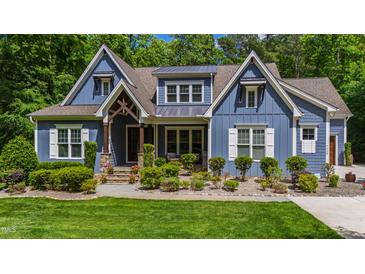 Charming blue two-story home with lush landscaping, covered porch, and stone accents at 7116 Dumfries Ln, Chapel Hill, NC 27514
