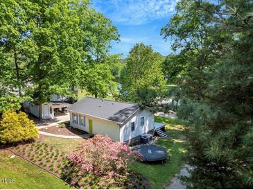 Inviting lake house showcasing lush landscaping, including vibrant azaleas, and a trampoline for outdoor fun at 135 Sagamore Dr, Louisburg, NC 27549