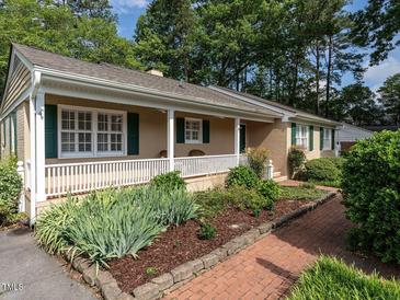 Charming tan home with a covered porch and a beautifully landscaped front yard at 2143 Ridge Rd, Raleigh, NC 27607