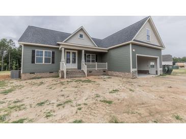 Charming single-story home featuring a covered porch, attached garage, and well-maintained siding at 25 Sanders Farm Dr, Smithfield, NC 27577